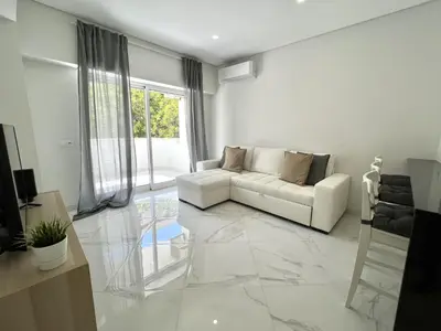 a living room with a white couch and a large window at Aman - Near the beach by HD PROPERTIES in Quarteira