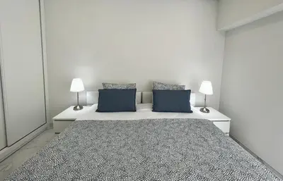 a white room with a bed with two blue pillows at Aman - Near the beach by HD PROPERTIES in Quarteira