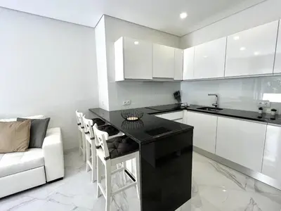 a kitchen with a black counter and white cabinets at Aman - Near the beach by HD PROPERTIES in Quarteira