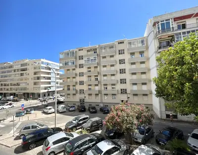 a parking lot with cars parked in front of a building at Aman - Near the beach by HD PROPERTIES in Quarteira