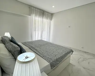 a white bedroom with a bed and a window at Aman - Near the beach by HD PROPERTIES in Quarteira