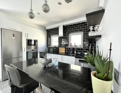 a kitchen with black and white appliances and a black brick wall at Nancy Apartment - Near Vilamoura Marina by HD PROP in Vilamoura