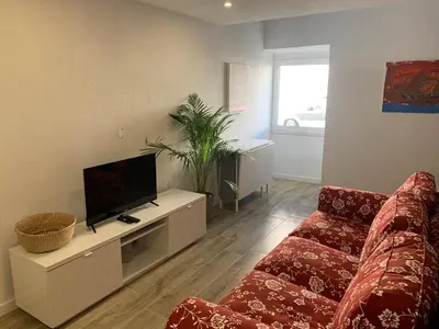 a living room with a red couch and a flat screen tv at CASA DAS CEGONHAS in Faro