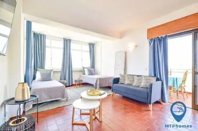 a living room with a blue couch and a bed at Amendoeiras by MTPhomes in Quarteira