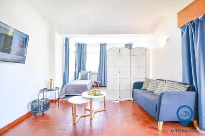 a bedroom with a bed with blue pillows and a window at Amendoeiras by MTPhomes in Quarteira