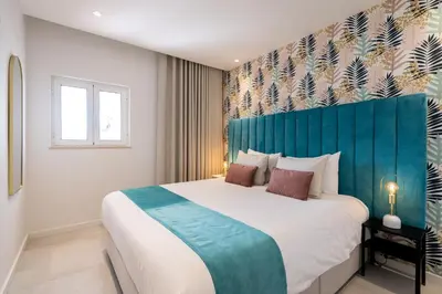 a bedroom with a large bed with a blue headboard at Apartamento Centro de Albufeira Sunny in Albufeira