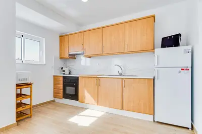 a kitchen with wooden cabinets and a white refrigerator at T1 Albufeira city centre in Albufeira
