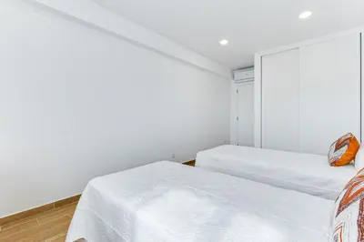 two beds in a room with white walls at T1 Albufeira city centre in Albufeira