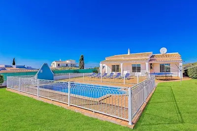a house with a metal fence in a yard at Casa Palmeira in Terras Novas