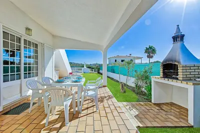 a patio with a table and chairs and a fireplace at Casa Palmeira in Terras Novas