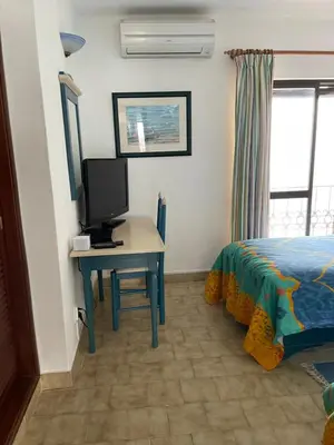 a bedroom with a desk with a tv and a bed at FeWo Cesar Manrique - Albufeira, Portugal in Albufeira