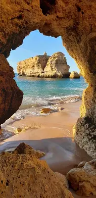 a view of the ocean from a cave on a beach at FeWo Cesar Manrique - Albufeira, Portugal in Albufeira