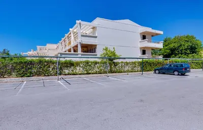 a parking lot with a tennis court in front of a building at AL - Barracuda Village in Vilamoura