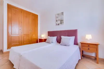 a bedroom with a white bed and a wooden door at AL - Colina Beach Holidays in Quarteira