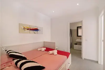 a white bedroom with a red and white bed at Large apartment in Vale do Lobo in Almancil
