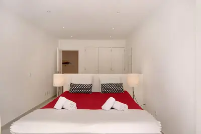 a bedroom with a large white bed with a red blanket at Large apartment in Vale do Lobo in Almancil