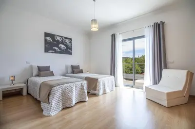 a bedroom with two beds and a chair and a window at Villa Maya in Almancil