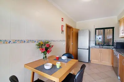a kitchen with a table with a vase of flowers on it at Casa dos Salgados in Albufeira