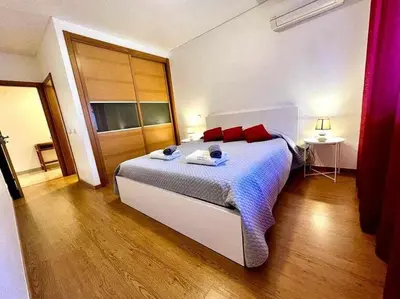 a bedroom with a large white bed with red pillows at Mar e Sol by - T3 , wi-fi e estacionamento in Quarteira
