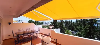 a balcony with tables and chairs and yellow umbrellas at Blue & Yellow Penthouse with Terrace at Balaia Mar in Albufeira