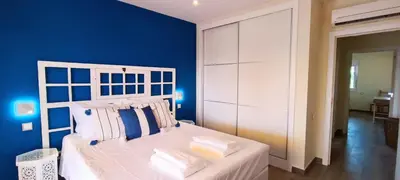 a bedroom with a white bed with a blue wall at Blue & Yellow Penthouse with Terrace at Balaia Mar in Albufeira