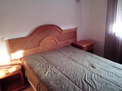 a bedroom with a bed with a wooden headboard and two tables at Beautiful 2-Bed Apartment in Olhos de Agua in Albufeira