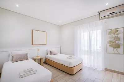 two beds in a white room with a window at Villa Kevin by Atlantic Places in Albufeira