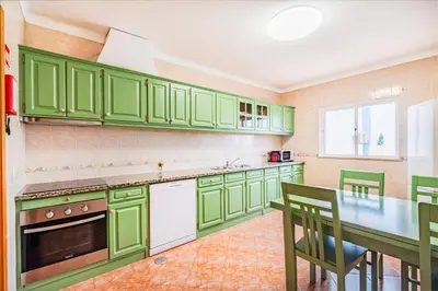 a kitchen with green cabinets and a table and chairs at Villa Kevin by Atlantic Places in Albufeira