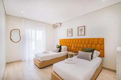 a bedroom with two beds and a large window at Villa Kevin by Atlantic Places in Albufeira