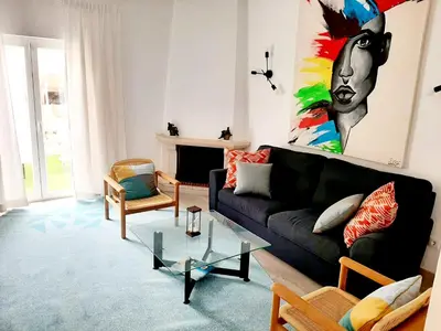 a living room with a black couch and a painting at Alojamento local 