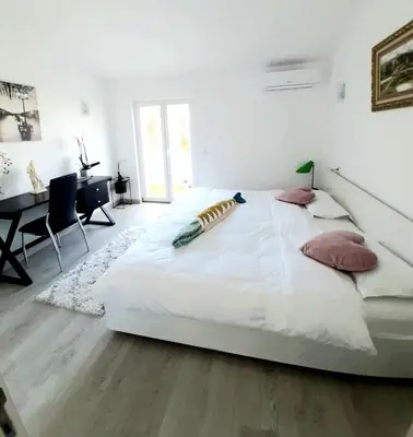 a large white bed in a room with a desk at Alojamento local 