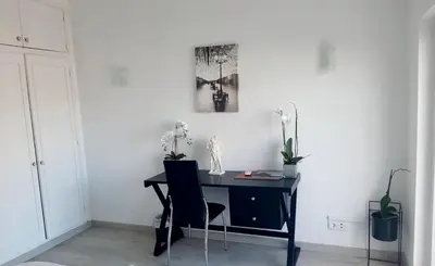 a black desk with two chairs and a picture on the wall at Alojamento local 