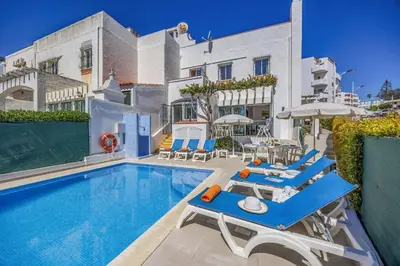 a swimming pool with blue and white chairs and umbrellas at Villa Alegre by Villa Plus in Albufeira