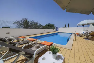 a swimming pool with lounge chairs and an umbrella at Villa Campos by Villa Plus in Guia