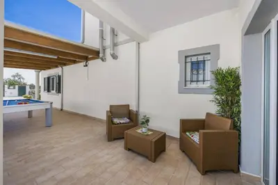a living room with chairs and a table and a window at Villa Casa Grande by Villa Plus in Albufeira
