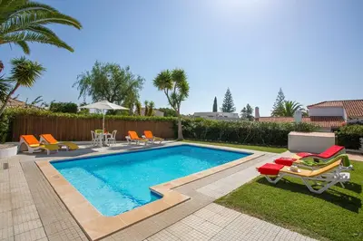 a swimming pool with chairs and a table and a tablektop at Villa Tupi by Villa Plus in Boliqueime