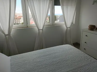 a bedroom with two windows with white curtains and a bed at Apartamento 90m2 com vista mar - Albufeira in Albufeira