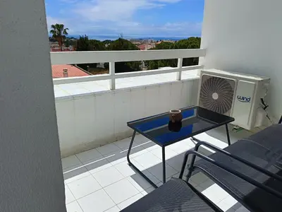 a balcony with a blue table and a fan at Apartamento 90m2 com vista mar - Albufeira in Albufeira
