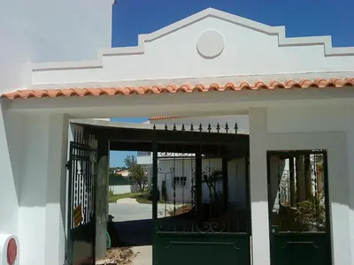 a white building with green doors and a gate at Remarkable 1-Bed Apartment in Olhos de Agua in Albufeira