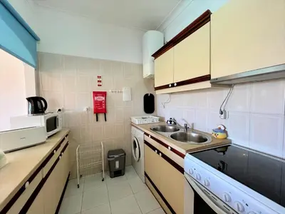 a small kitchen with a sink and a microwave at Albufeira Classic 1 With Pool by Homing in Albufeira