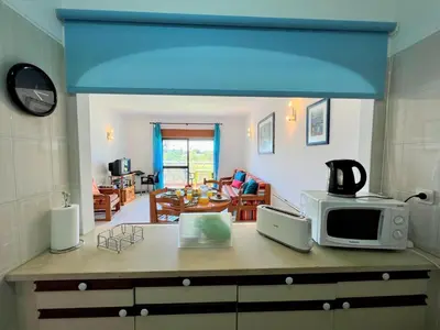 a kitchen with a microwave and a living room at Albufeira Classic 1 With Pool by Homing in Albufeira