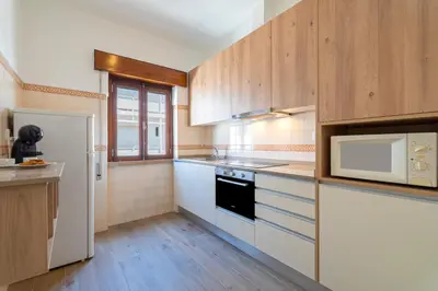 a kitchen with white appliances and wooden cabinets at Ténis Mar F in Albufeira