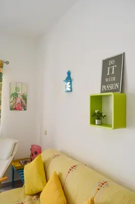 a living room with a yellow couch and a sign on the wall at BeGuest Feliz Choro Apartment in Branqueira