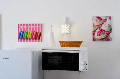 a microwave on top of a refrigerator with a painting at BeGuest Feliz Choro Apartment in Branqueira