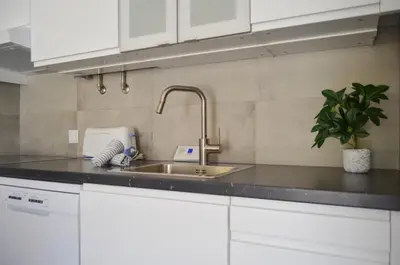 a kitchen with white cabinets and a sink at BeGuest Feliz Choro Apartment in Branqueira