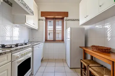 a kitchen with white appliances and a white refrigerator at Ténis Mar E in Albufeira