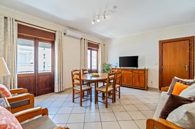 a living room with a table and chairs and a tv at Ténis Mar E in Albufeira