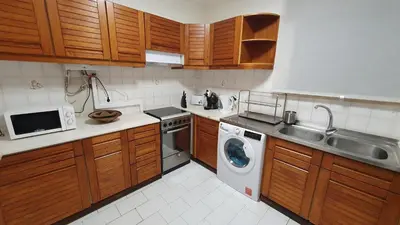 a kitchen with wooden cabinets and a washing machine at BeGuest Areias Apartment in Albufeira