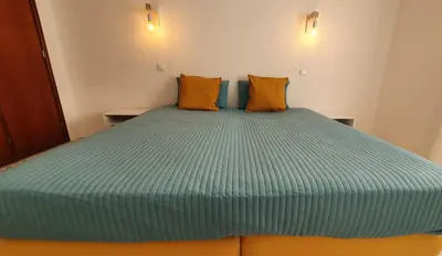 a bedroom with a large blue bed with orange pillows at BeGuest Areias Apartment in Albufeira