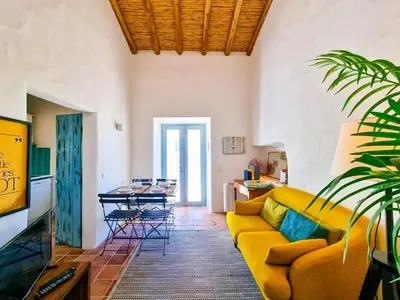 a living room with a yellow couch and a table at FLH Vale Judeu Rustic Mezzanine Cottage I in Loulé